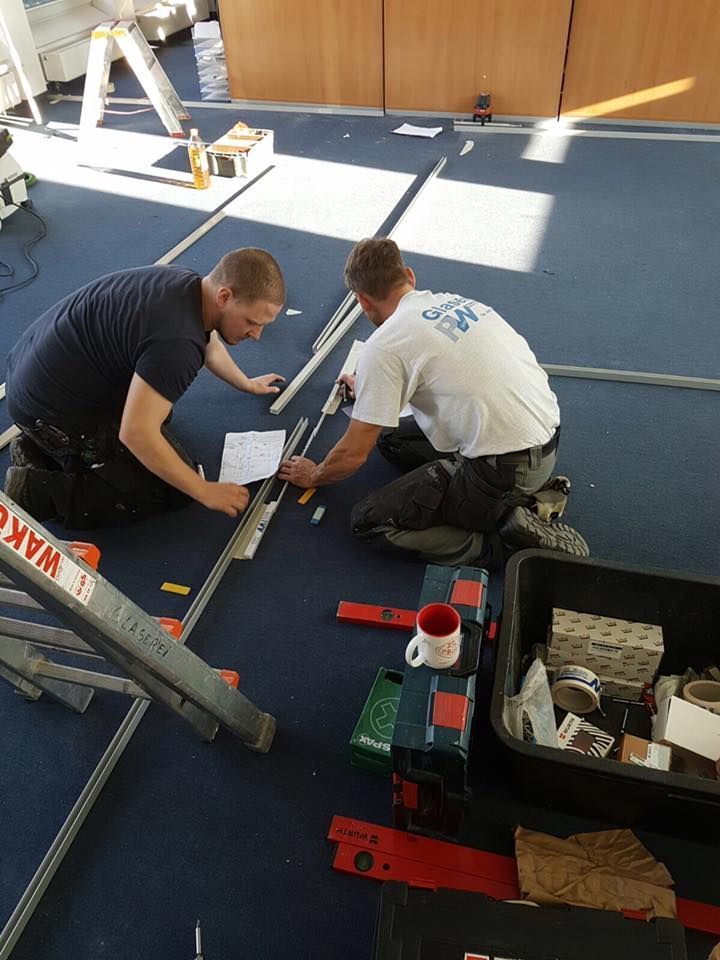 Zwei Männer arbeiten auf einem blauen Teppich mit einer Leiter, auf der Wachs steht