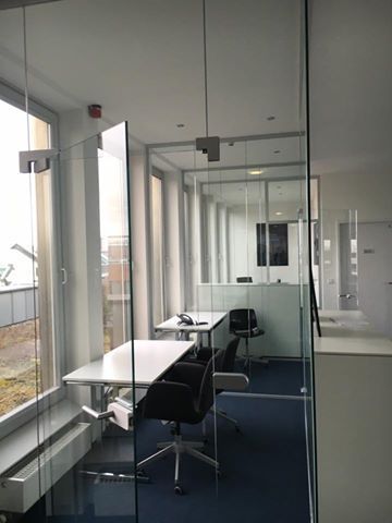 Ein Raum mit einer Glaswand und Tischen und Stühlen darin.