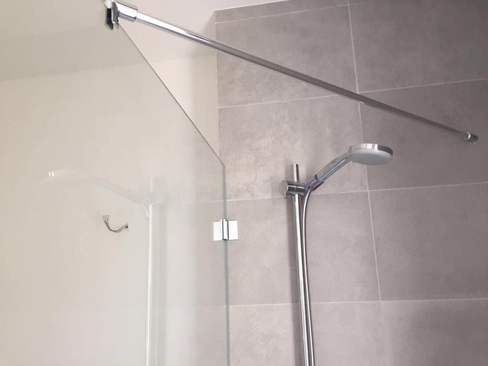 Eine Duschkabine mit Glastür und Duschkopf.