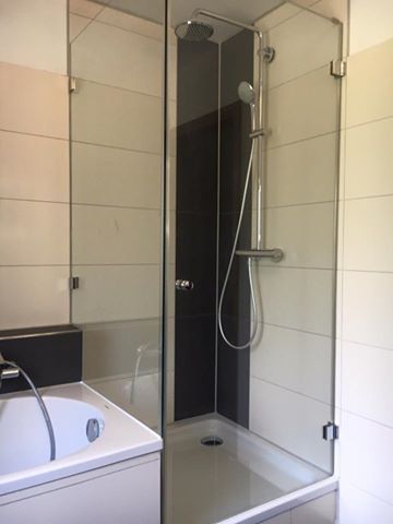 Ein Badezimmer mit Badewanne und Duschkabine mit Glastür.