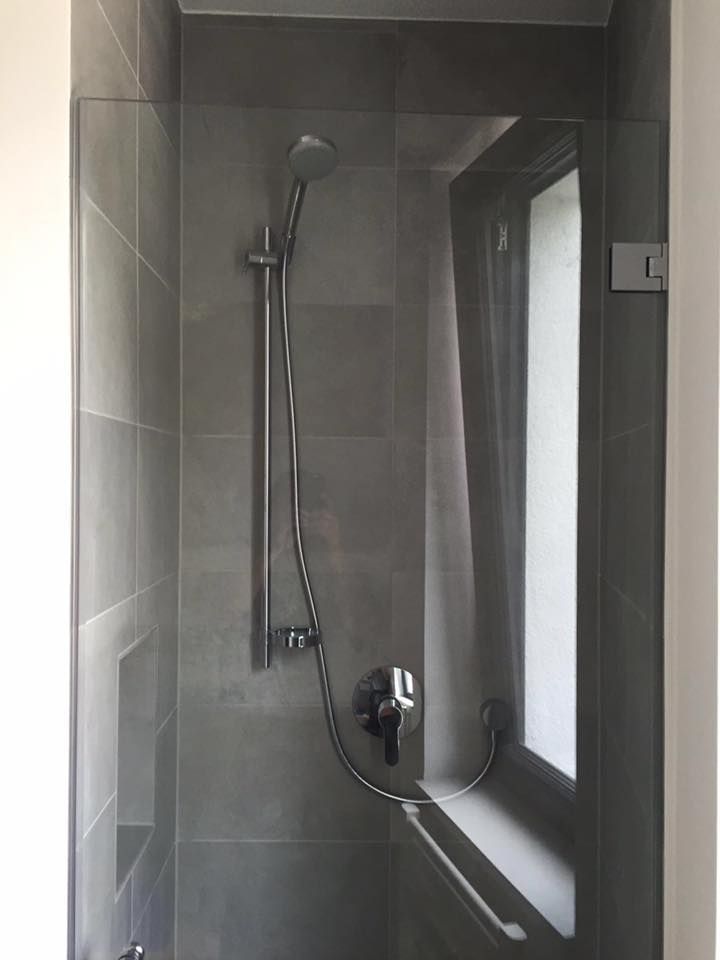 Eine Duschkabine mit Glastür und Fenster.