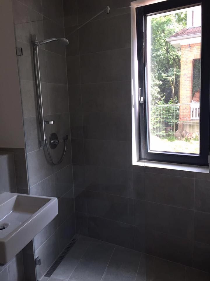 Ein Badezimmer mit Waschbecken, Dusche und Fenster.