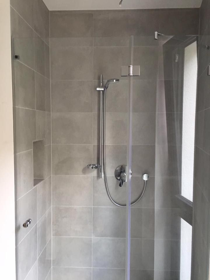 Eine Duschkabine mit Glastür und Duschkopf.