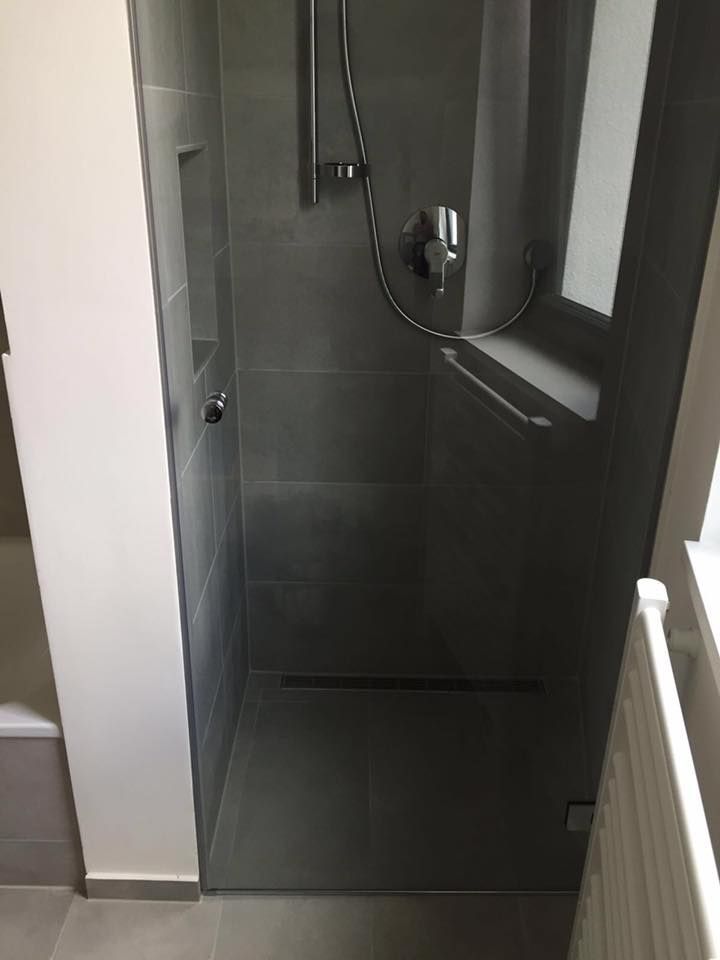Ein Badezimmer mit ebenerdiger Dusche mit Glastür.