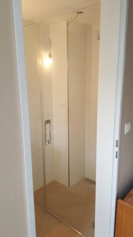 Ein Badezimmer mit ebenerdiger Dusche und Glastür.