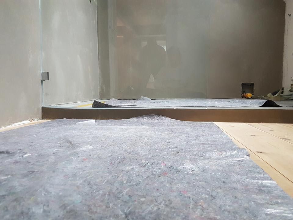 Ein Raum mit Holzboden und einer grauen Plane auf dem Boden.