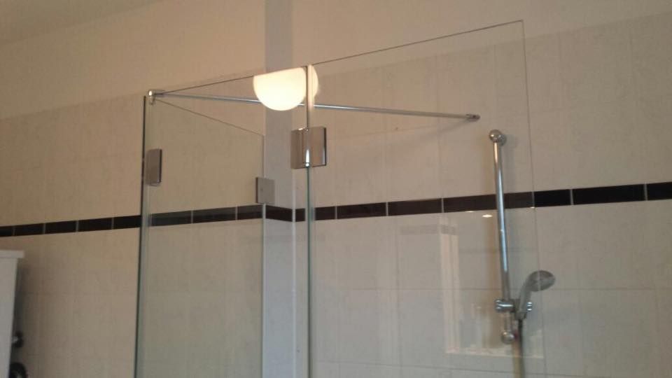 Ein Badezimmer mit Glasduschtür und Duschkopf.