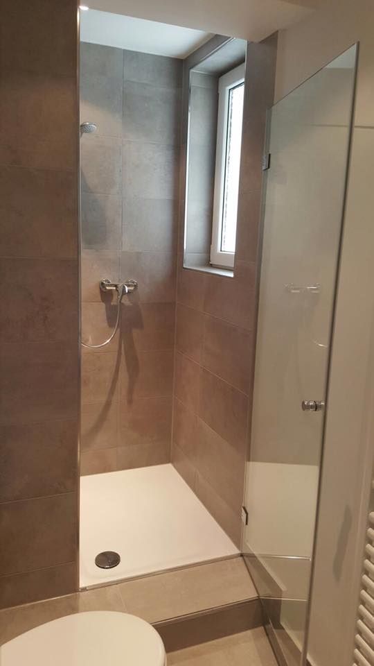 Ein Badezimmer mit Toilette, Dusche und Fenster.