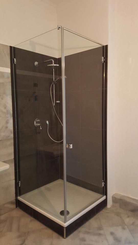 Eine Duschkabine mit Glastür und Duschkopf in einem Badezimmer.