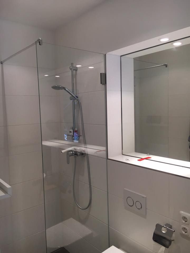 Ein Badezimmer mit ebenerdiger Dusche, Toilette und Spiegel.