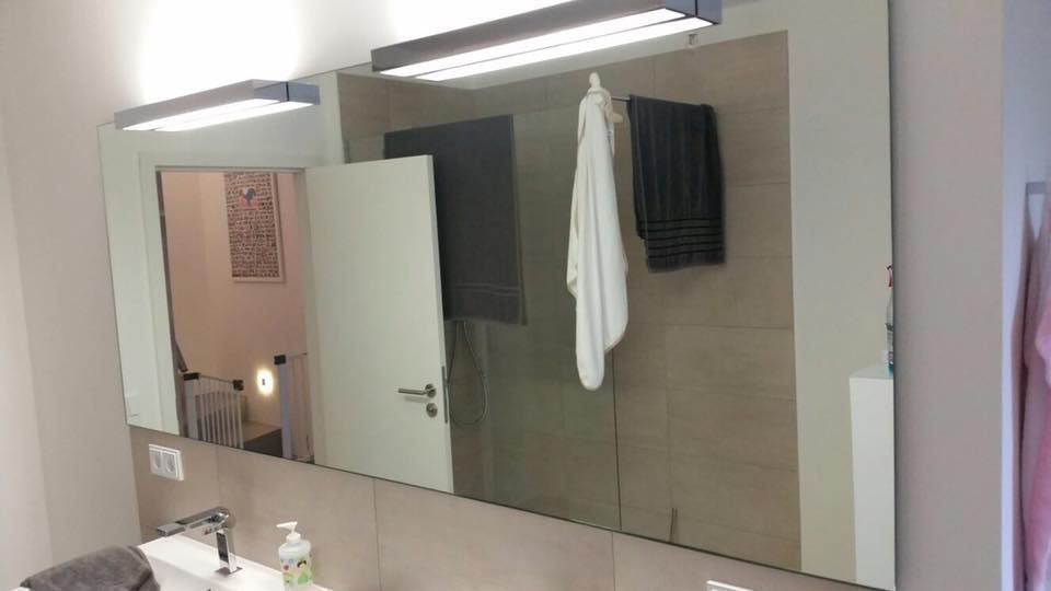 Ein Badezimmer mit großem Spiegel und Waschbecken.