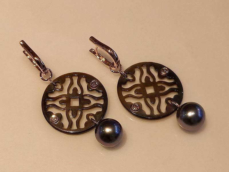 Ein Paar Ohrringe mit einer daran hängenden schwarzen Perle