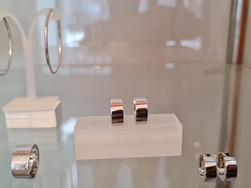 Ein Paar Ohrringe und ein Ring sind auf einem Glasregal ausgestellt.