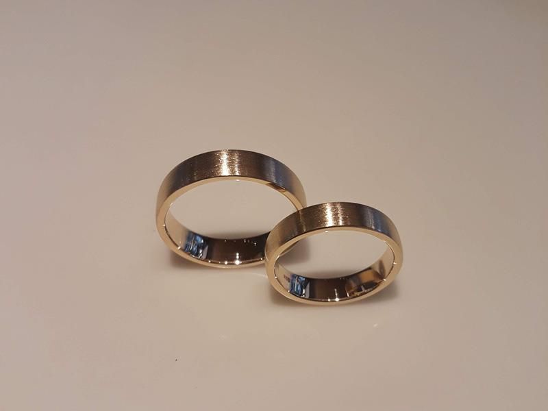 Ein Paar goldene Eheringe auf einer weißen Oberfläche