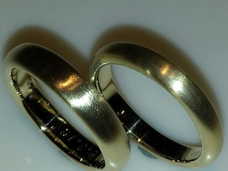 Ein Paar goldene Eheringe auf einer weißen Oberfläche