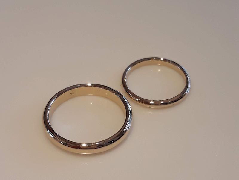 Zwei goldene Ringe liegen auf einer weißen Oberfläche