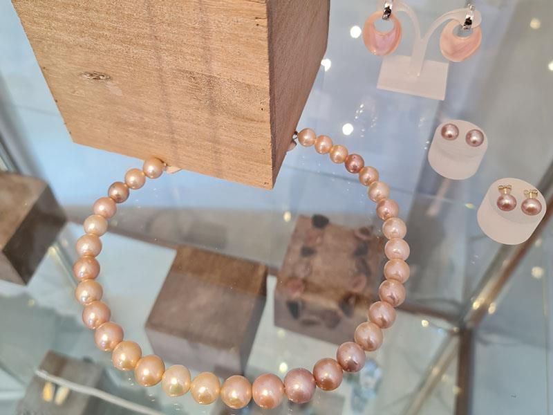 Eine Halskette und Ohrringe liegen auf einem Glastisch.