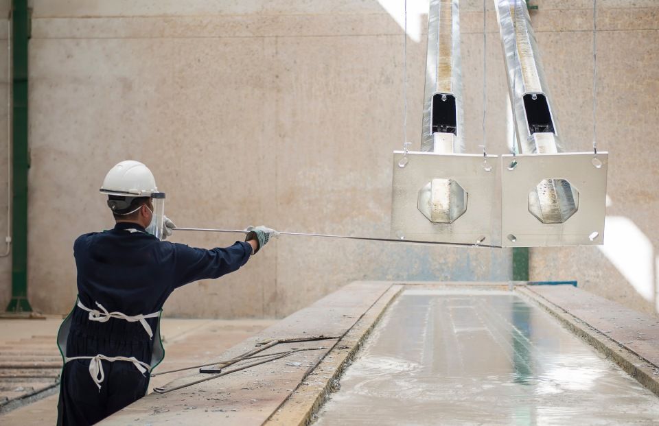 Ein Mann mit Schutzhelm und Maske besprüht einen Metallgegenstand.