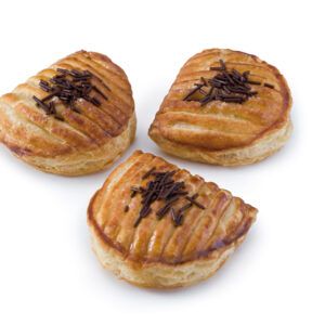 Três pastéis com granulado de chocolate sobre uma superfície branca