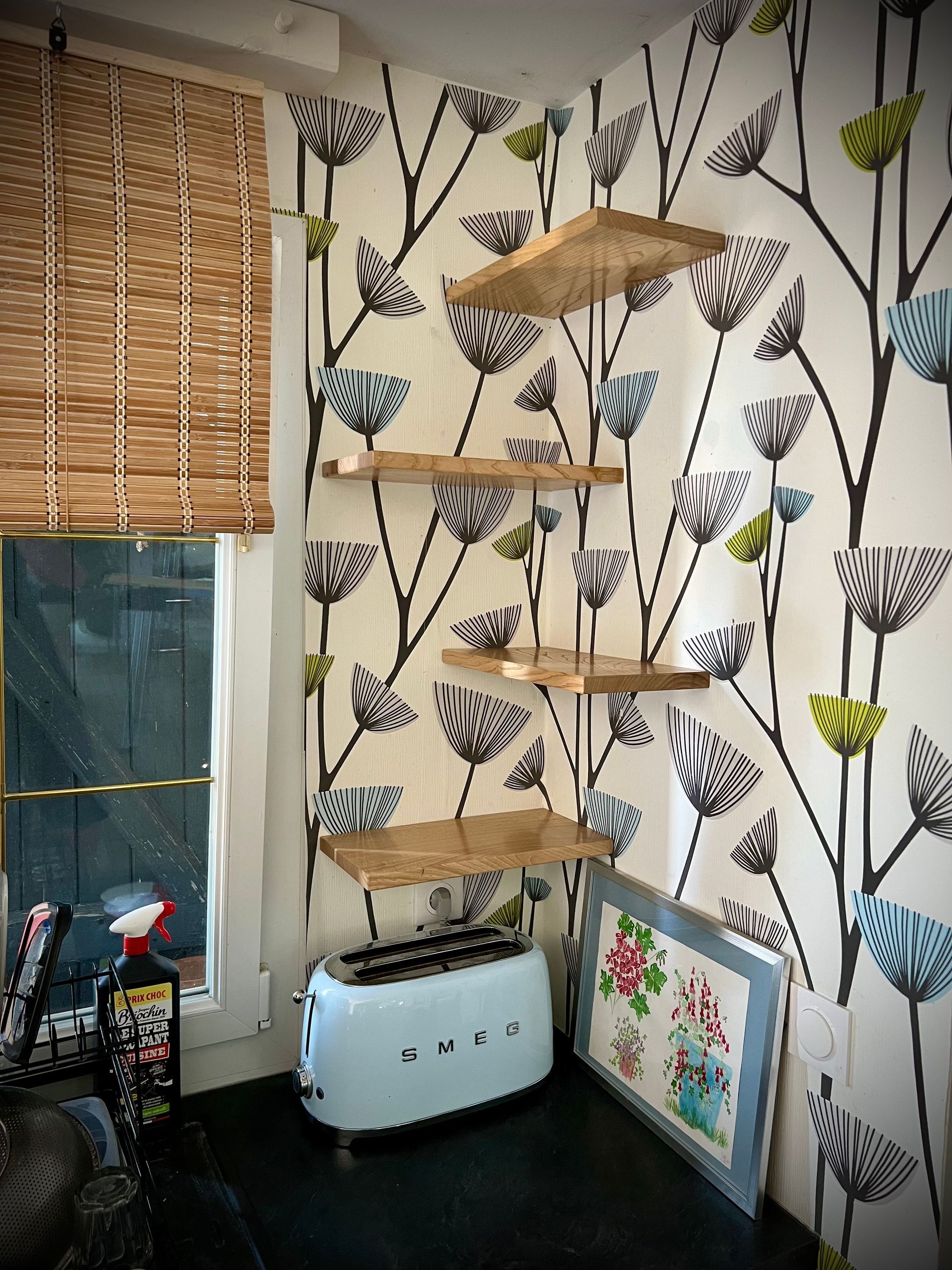 Coin douillet pour chat avec étagères murales, store en bambou et papier peint fleuri à motifs d'oiseaux.