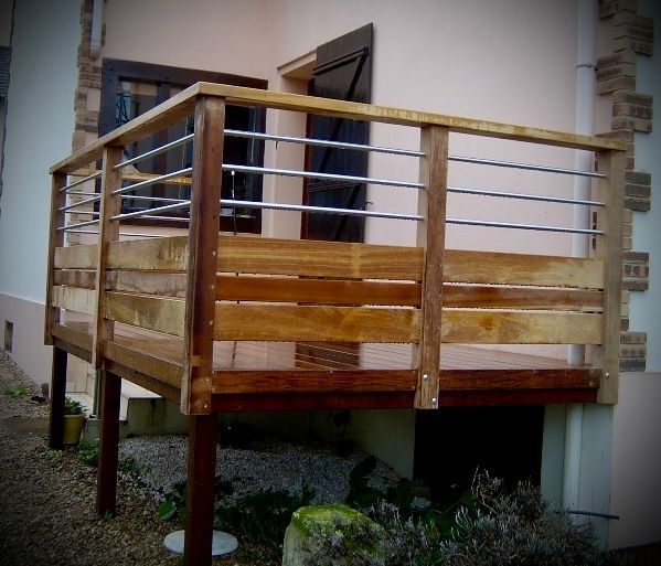 Balcon en bois attenant à la maison, avec rambarde métallique et porte donnant sur celle-ci