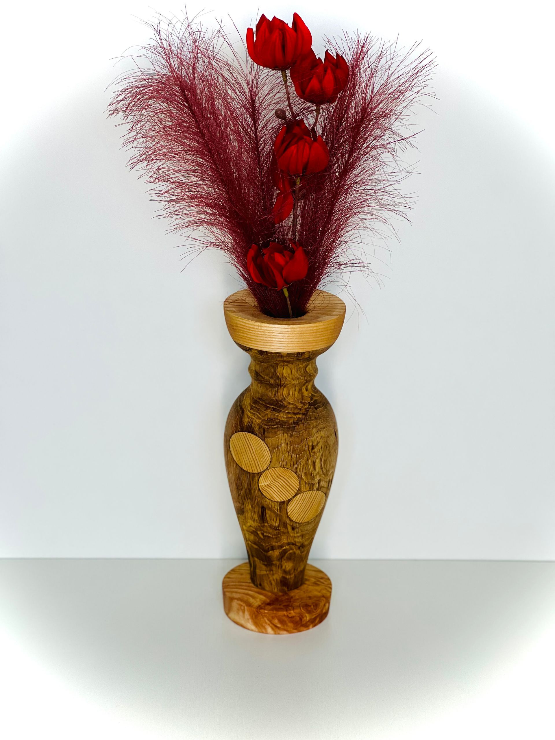Vase décoratif doré avec composition florale rouge.