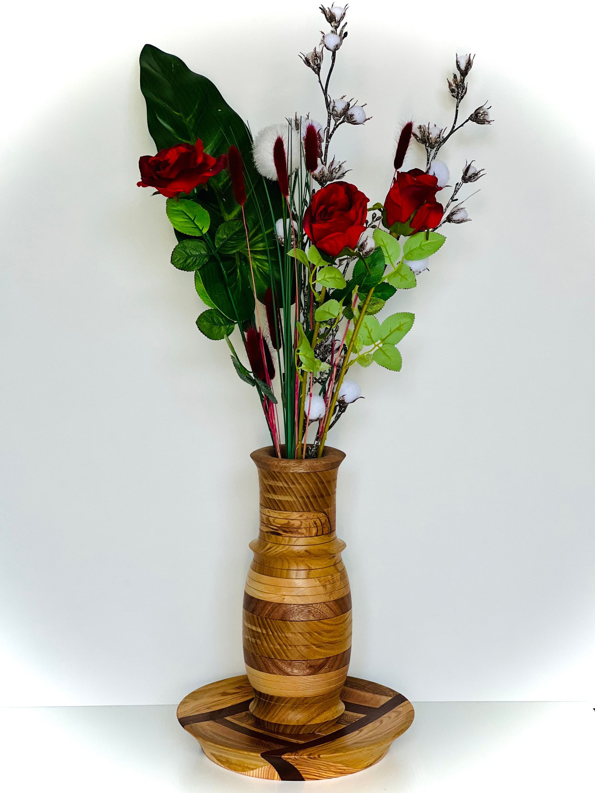 Vase décoratif en bois avec des roses rouges et de la verdure sur fond blanc