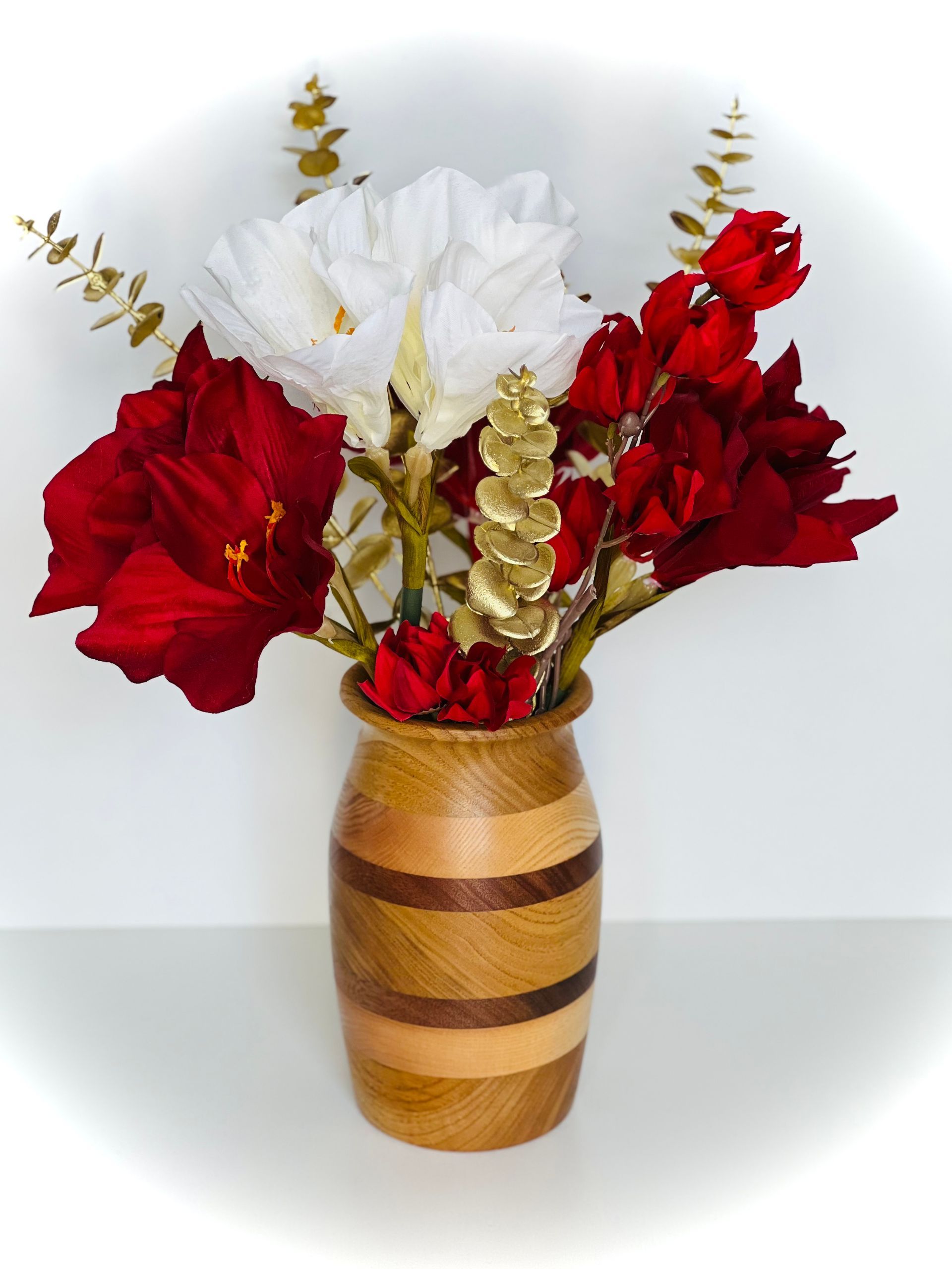 Fleurs rouges et blanches dans un vase en bois rayé sur une surface blanche