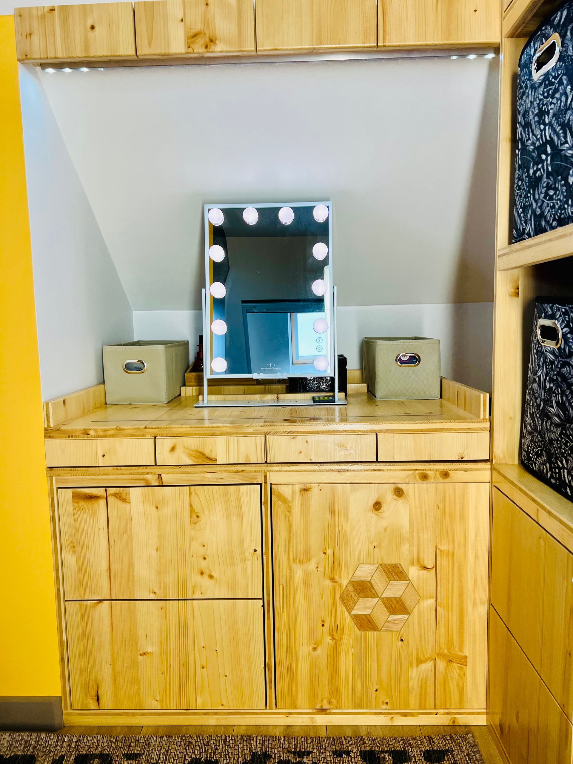 Meuble-lavabo en bois avec miroir éclairé, vasques à poser et tiroirs dans une petite pièce.