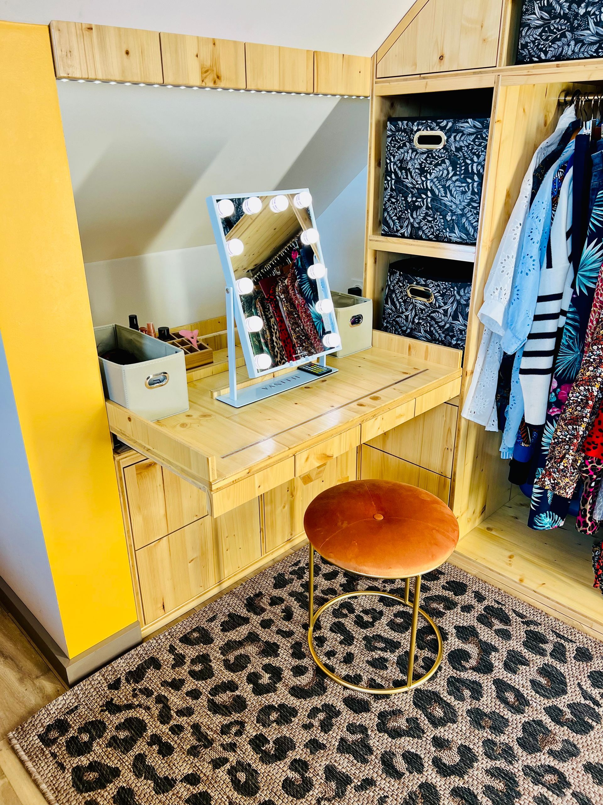 Coiffeuse en bois avec miroir, tabouret orange, penderie ouverte et tapis à motifs dans une chambre confortable