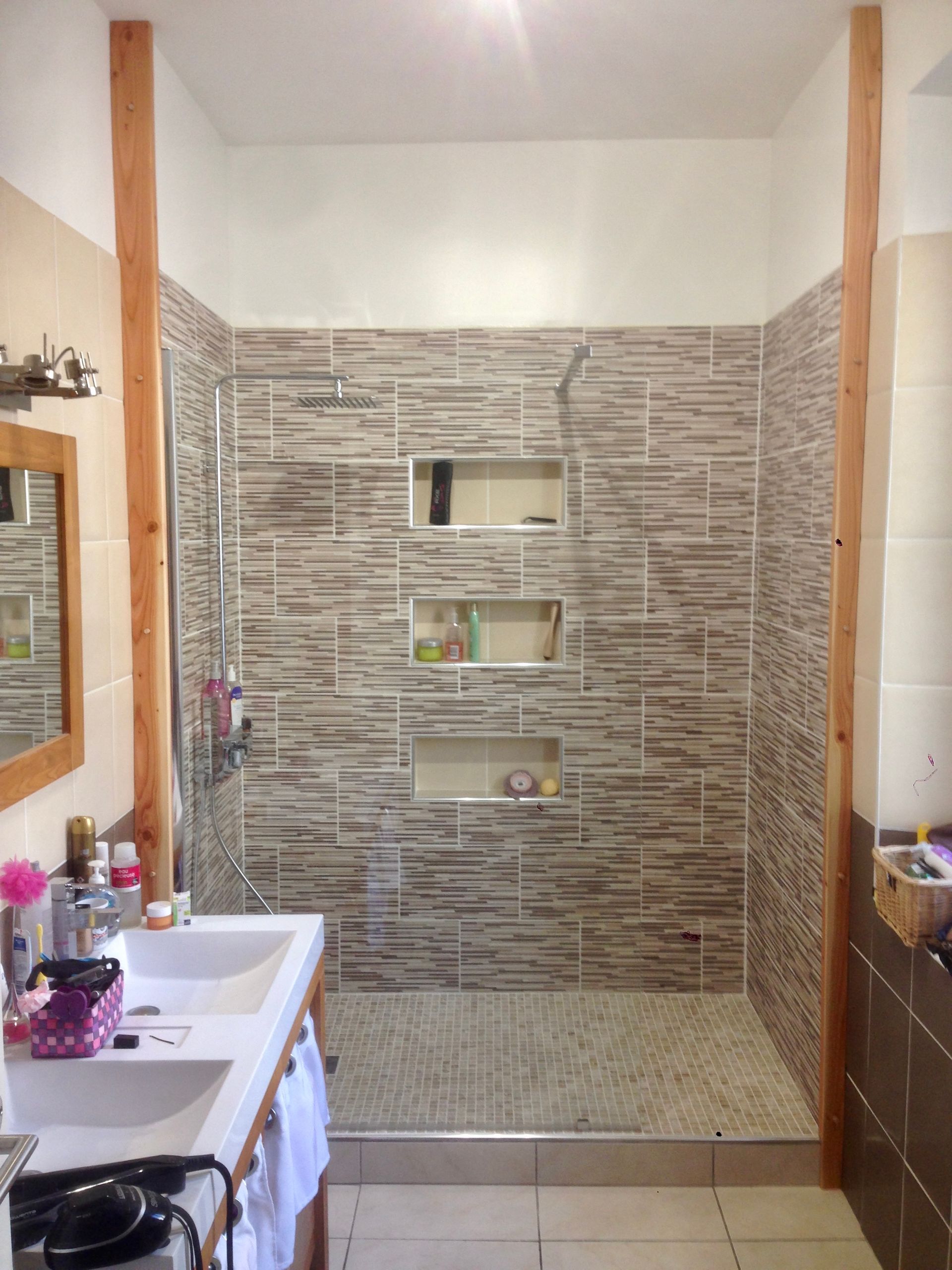 Salle de bains avec douche à l'italienne carrelée, paroi sans verre et meuble-lavabo au premier plan.