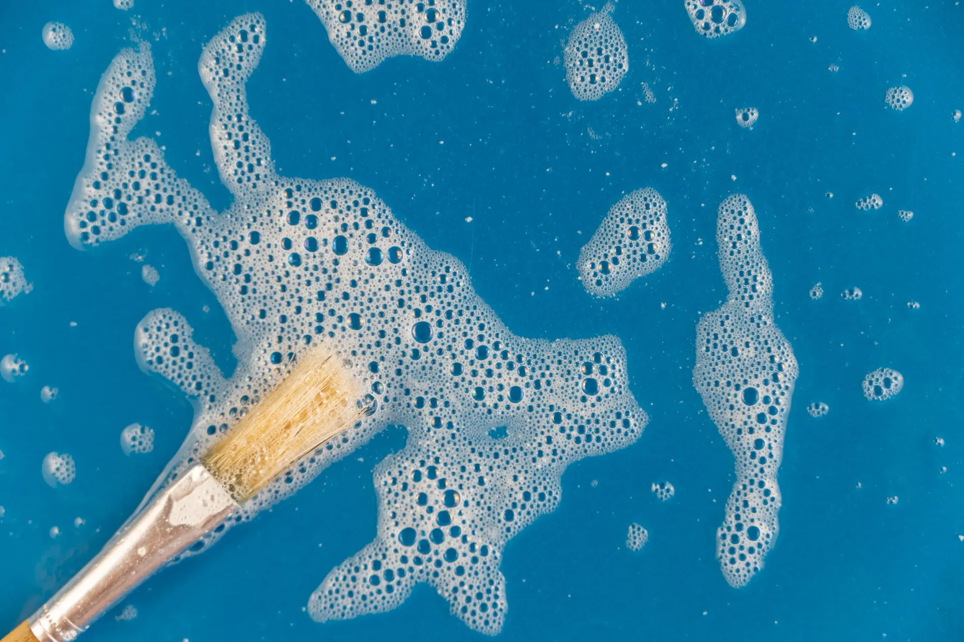 Pinte con pincel en agua azul jabonosa, creando patrones de espuma blanca.