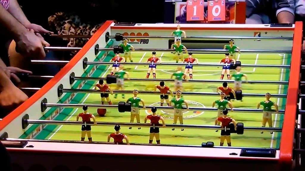 Futbolín con figuras rojas y verdes jugando un partido. El marcador muestra al equipo rojo con 10.