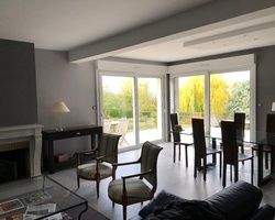 Salon avec cheminée, portes coulissantes en verre donnant sur une cour arrière, table à manger et chaises.
