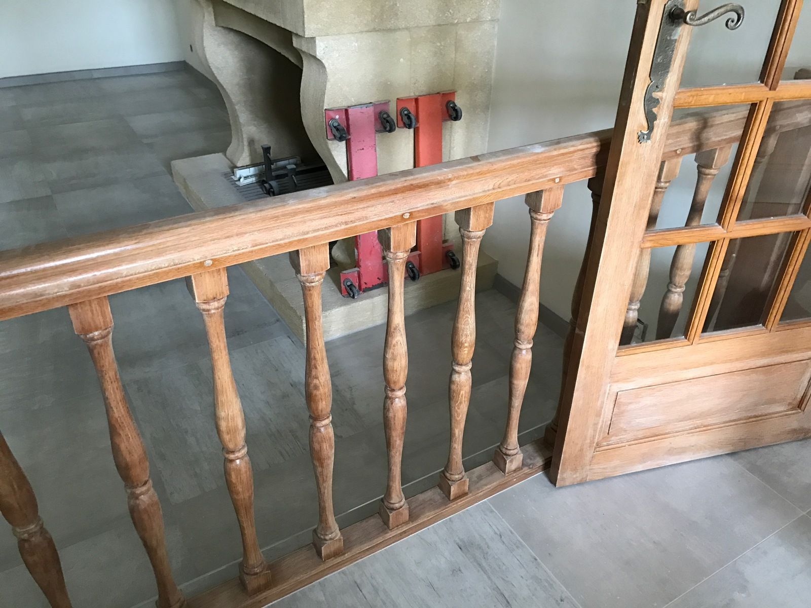 Rambarde et porte en bois posées sur un sol carrelé près d'une cheminée.