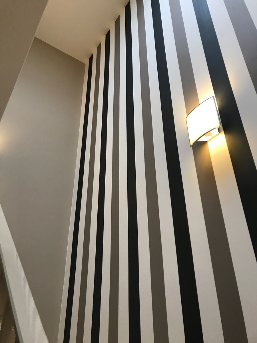 Salon avec télévision sur panneau de bois, flanqué de deux portes bleues et de murs à la texture sombre.