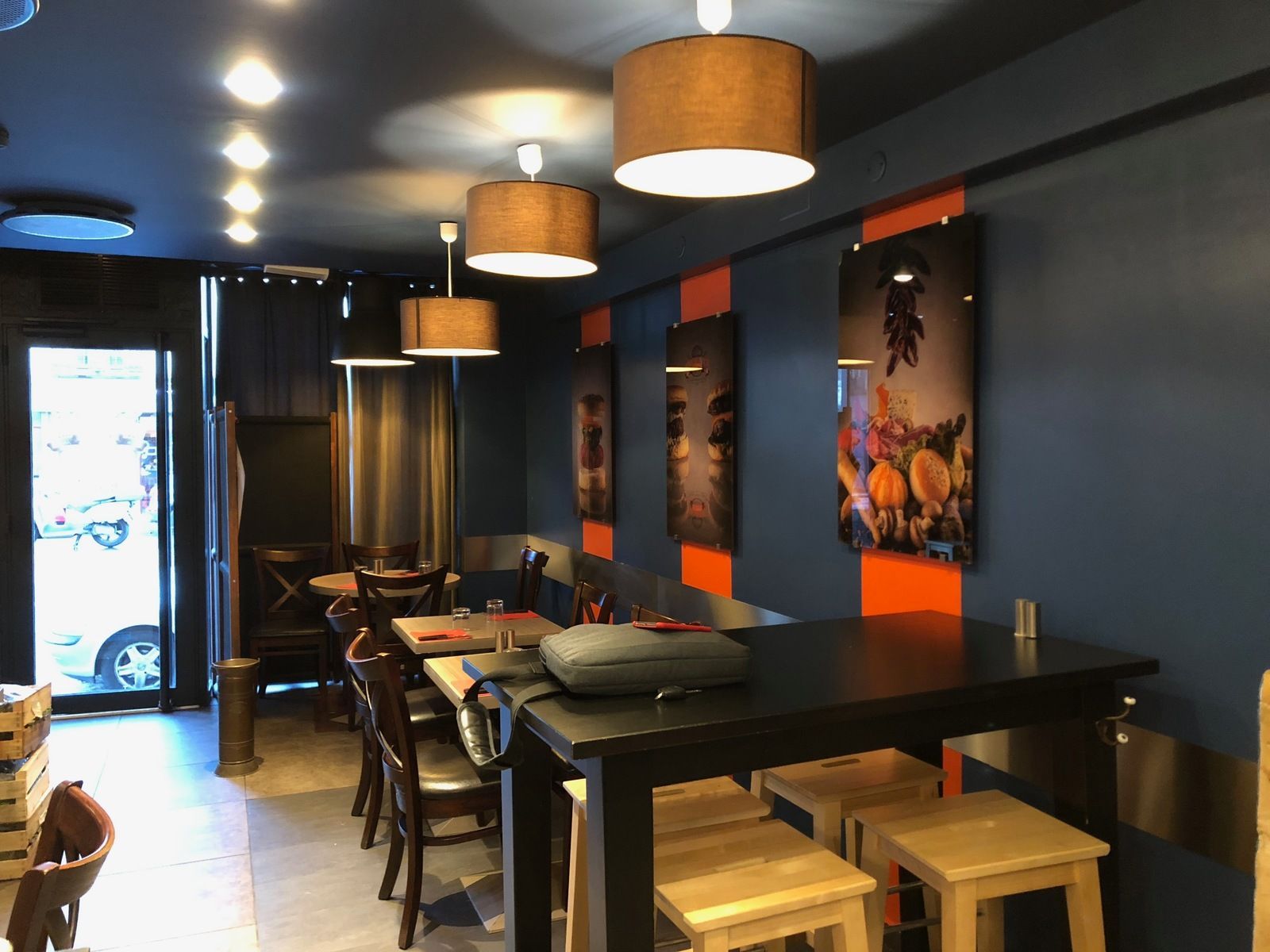 Intérieur d'un café aux murs bleu foncé, touches d'orange, tables et tabourets en bois.