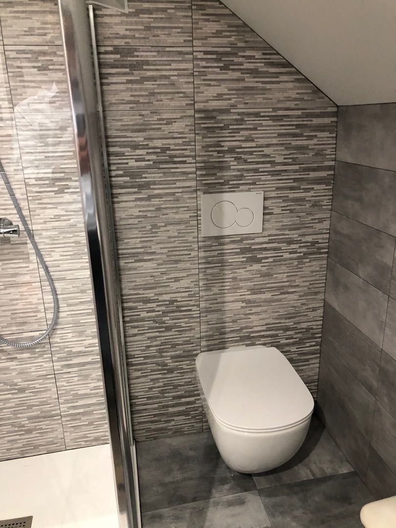 Salle de bains avec murs carrelés gris, toilettes suspendues et cabine de douche.