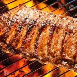 Una parrilla de costillas a la parrilla sobre brasas calientes, que lucen doradas y jugosas en una parrilla de barbacoa.
