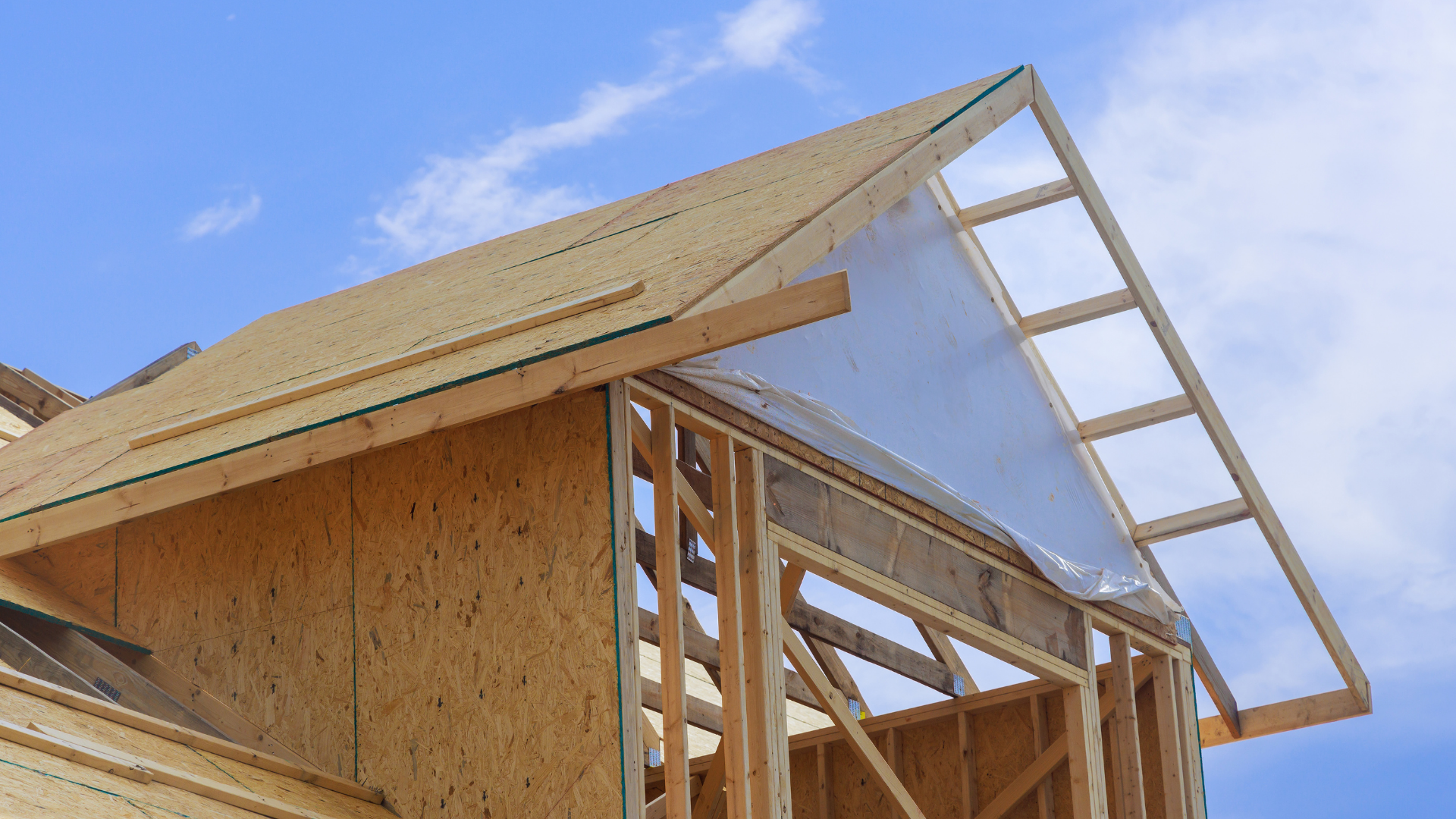 Une maison en bois est en construction avec un ciel bleu en arrière-plan.