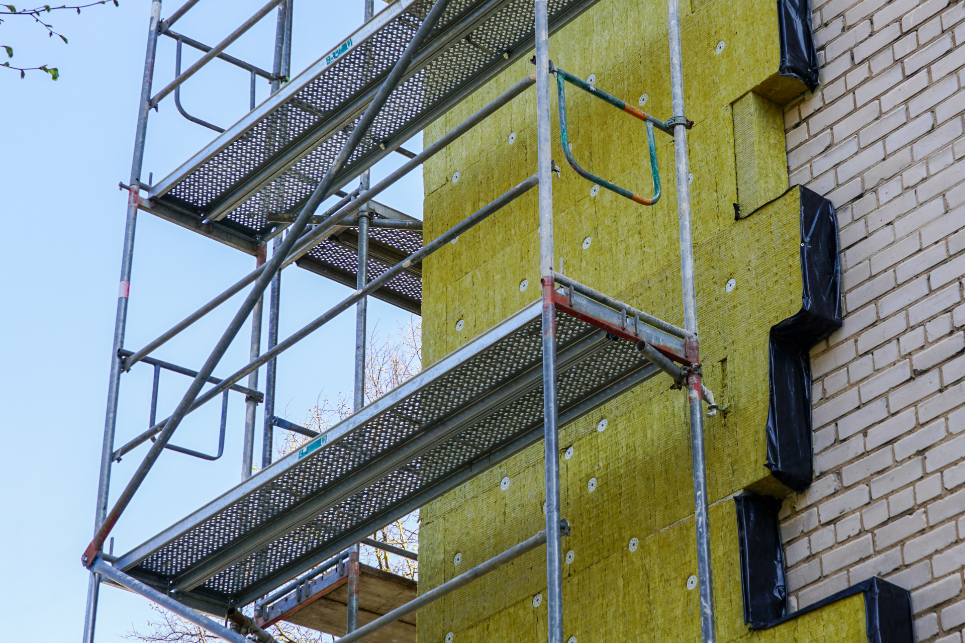Un échafaudage est utilisé pour isoler le côté d'un bâtiment en briques.