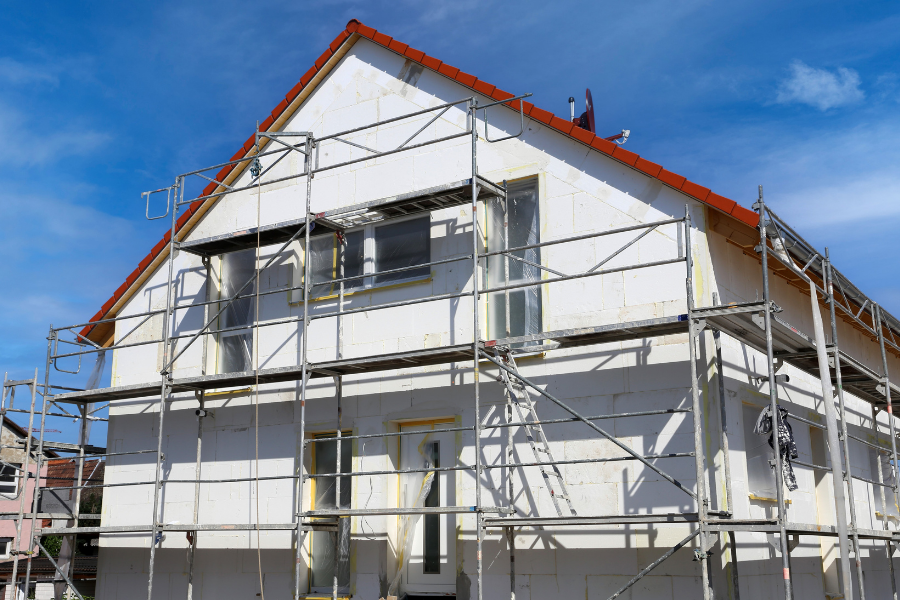 Une maison est en construction avec des échafaudages autour.