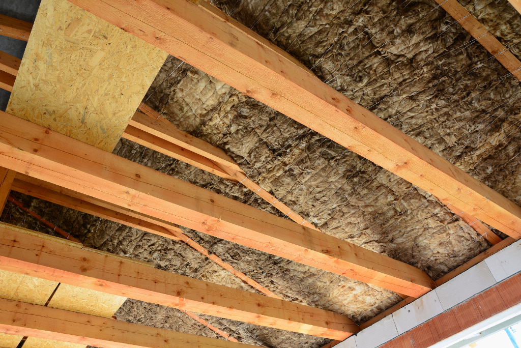Le plafond d'un bâtiment avec poutres en bois et isolation.