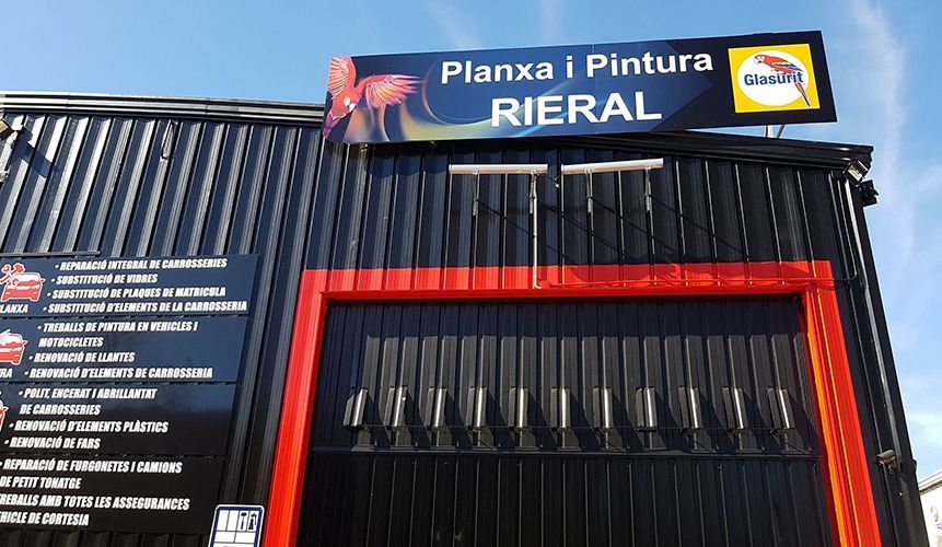 Edificio negro con puerta con marco rojo y un cartel con el texto