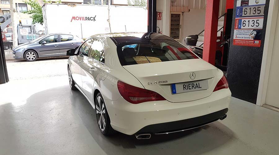 Un Mercedes CLA cupé blanco está estacionado en un garaje. La matrícula dice 