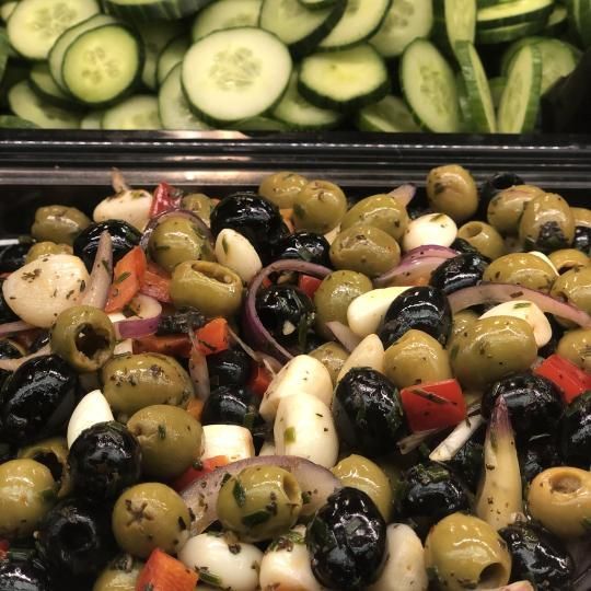 Sekoitus oliiveja ja viipaloituja kurkkuja myyntitiskillä tarjottimella