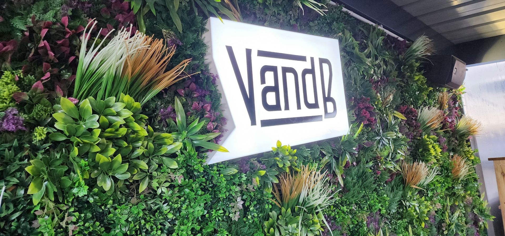 Logo de l'enseigne V and B dans un mur végétal
