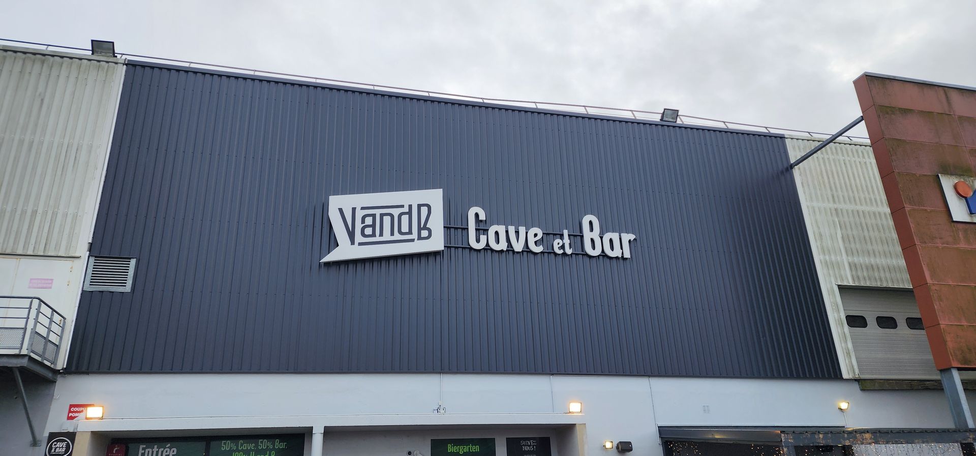 Panneau V and B Cave et Bar sur un bâtiment à l'extérieur gris.