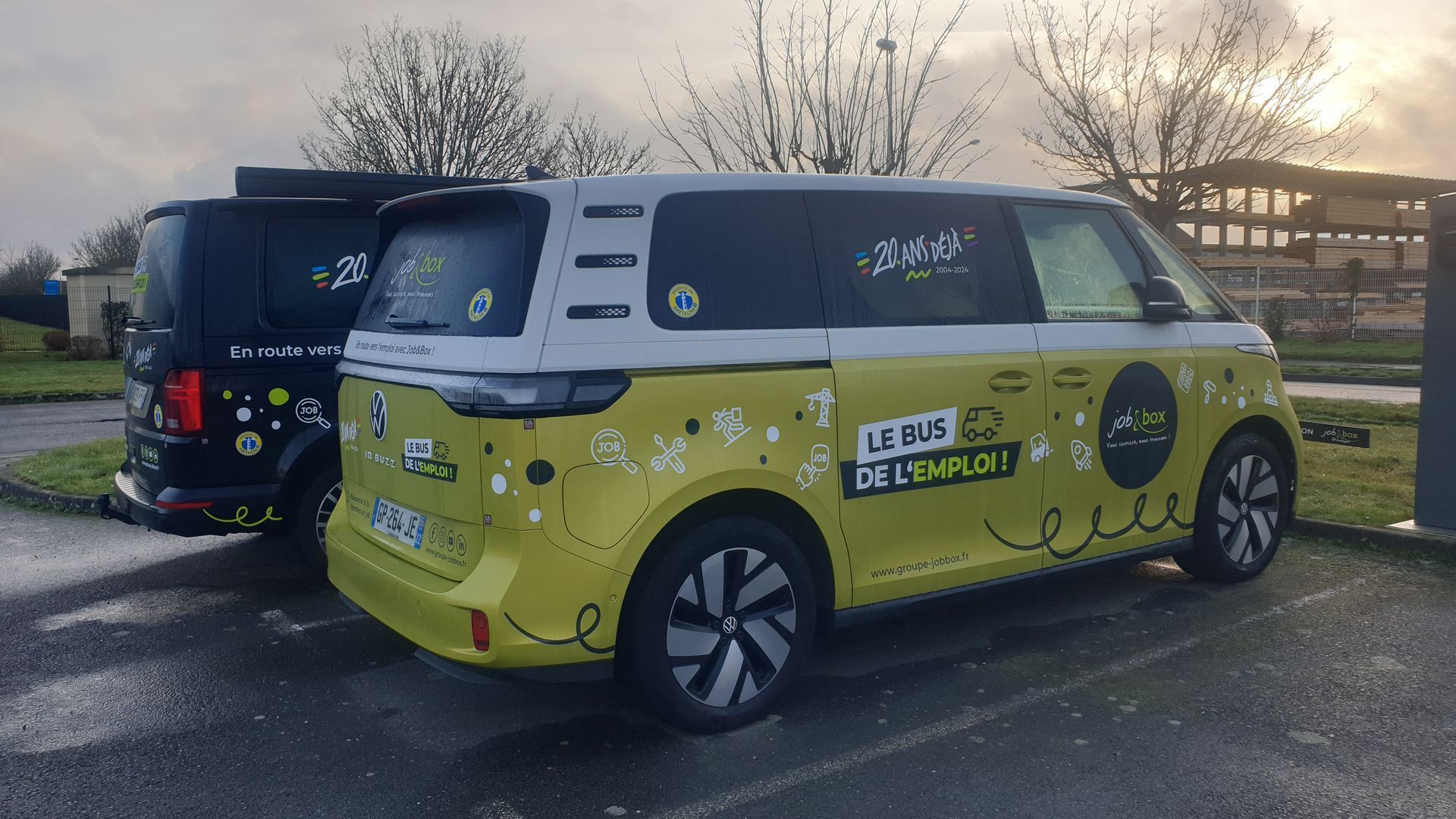 Deux fourgons Volkswagen ID. Buzz colorés garés dehors. L'un est jaune, l'autre noir.