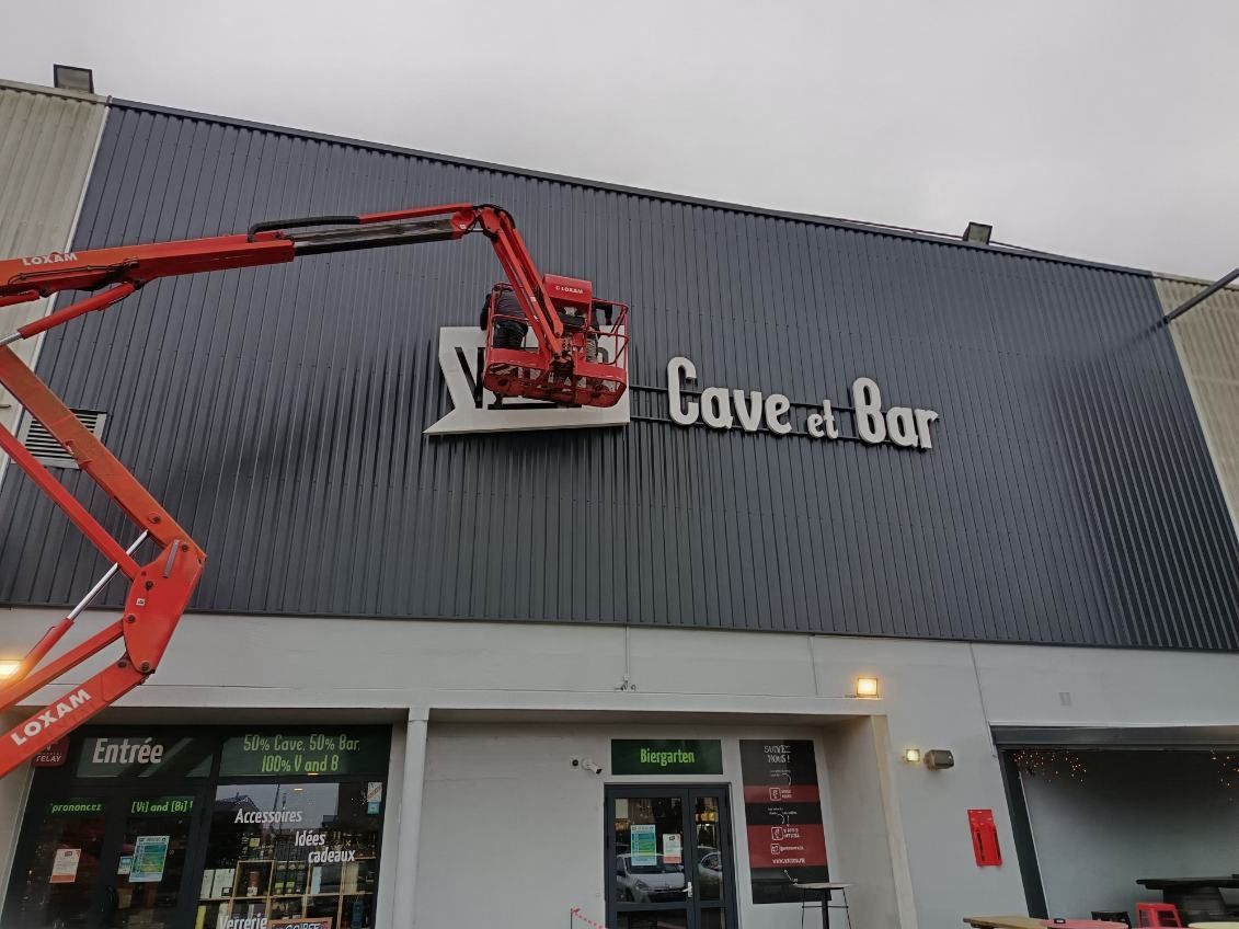 Panneau en bois avec lettres noires, entouré de verdure.